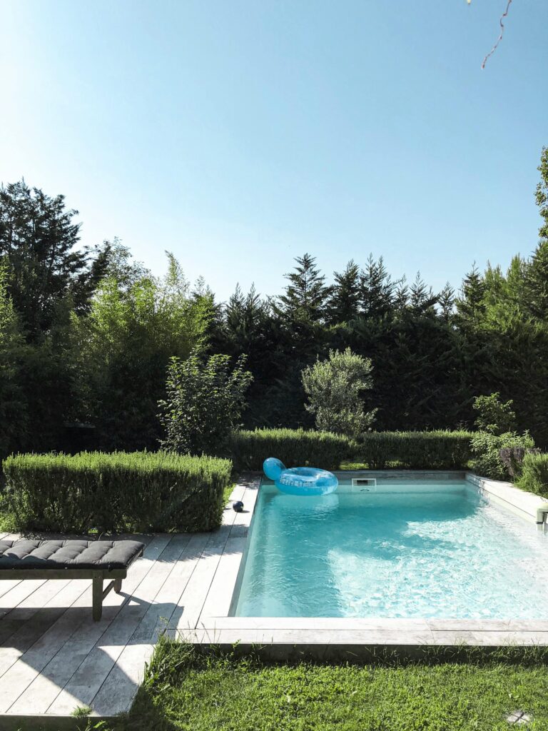 Quiet backyard pool surrounded by greenery and blue skies, ideal for relaxation.